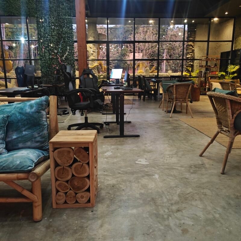 Bamboo sofa with teal cushions sits next to a wooden log side table in a cafe