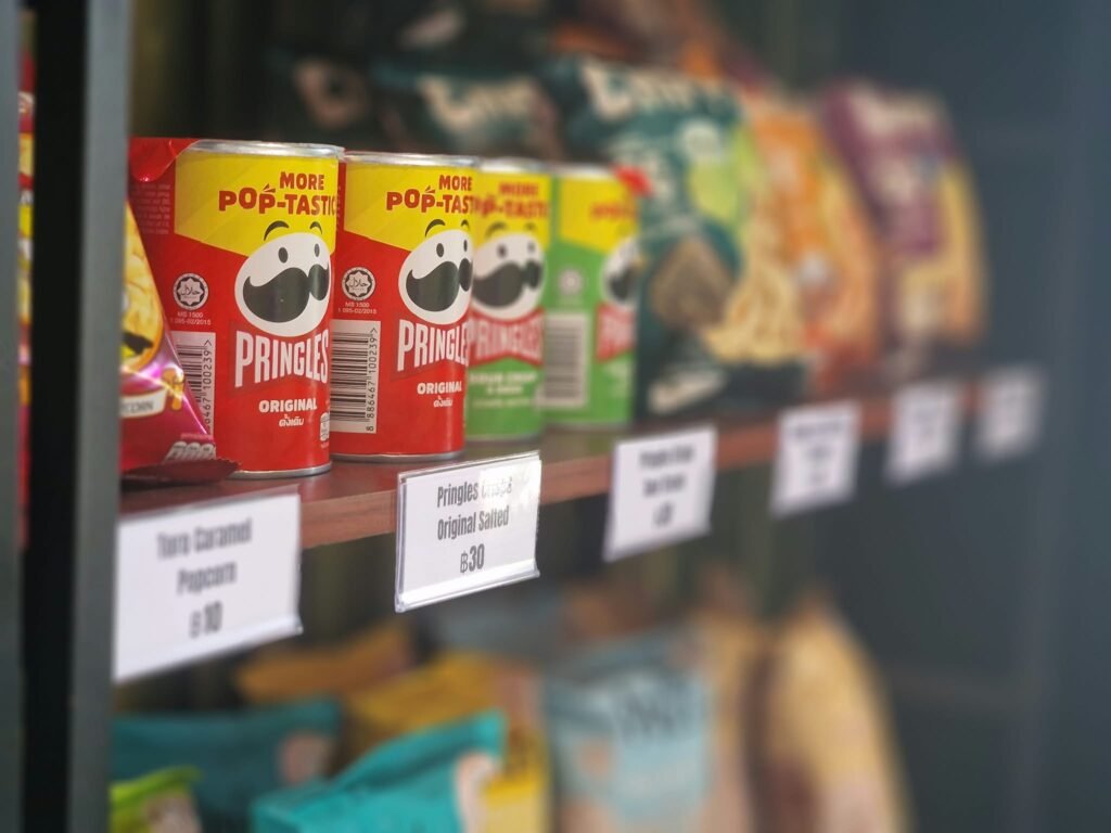 Pringles and popcorn cans displayed on a shelf with price tags